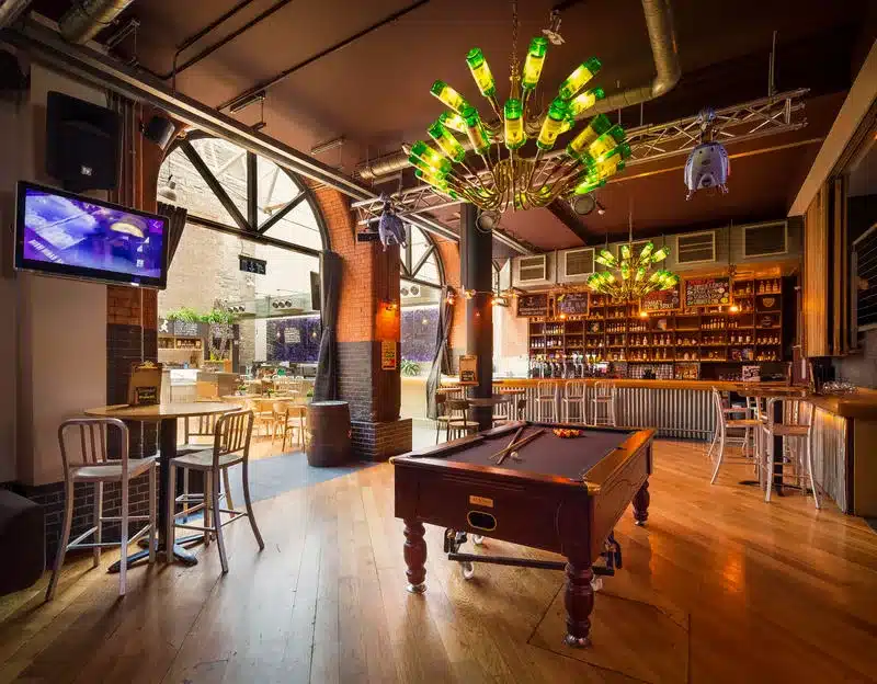 Are Hostels Safe? Honest Experiences from a Decade of Travel + 10 Takeaways 5 Bar and pool table at the Generator Hostel Dublin, with chandeliers made of Jameson Irish Whiskey bottles hanging over the room.