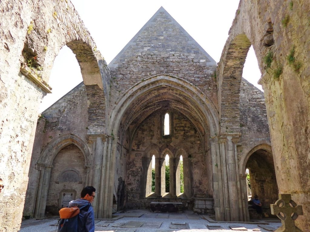 Honest Thoughts on Taking Paddywagon Tours from Dublin to the Cliffs of Moher 3 Stone interior of Corcomroe Abbey, a 12th-century Cistercian abbey ruin, with vaulted arches, weathered stone walls, and soft natural light filtering through narrow Gothic windows, in County Clare, Ireland.