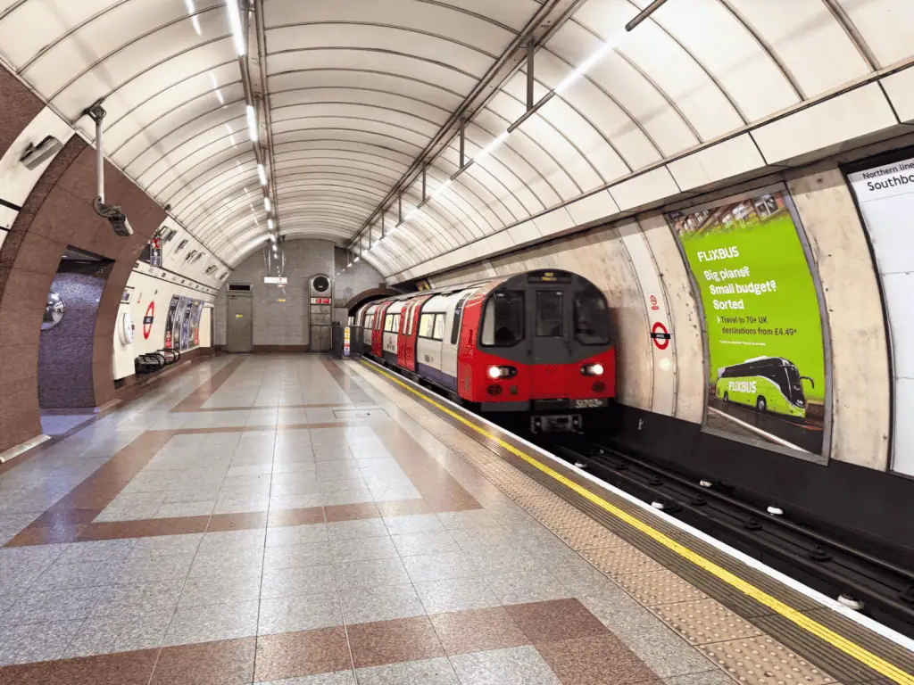 Reviewing Astor Oxford Street: Is It a Safe Hostel to Stay at in Soho, London? 3 Interior of a London Underground tube station: spacious platform with tiled walls and a London‑style subway train approaching under fluorescent lights in England, United Kingdom.