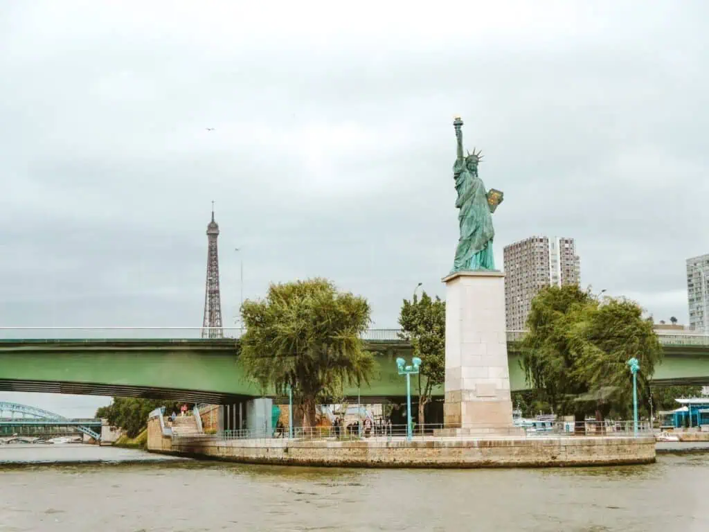 How to Spend a Day in Paris, France: An Affordable, Speedy Itinerary 21 View of the Eiffel Tower and a replica of the Statue of Liberty as seen from a Seine River cruise in Paris. A scenic and iconic experience often included in a well-planned Paris itinerary.
