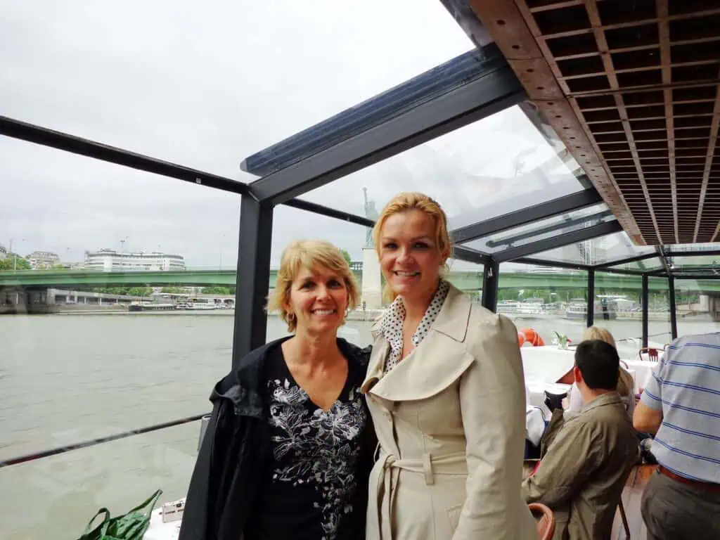How to Spend a Day in Paris, France: An Affordable, Speedy Itinerary 20 Two women enjoying a Seine River cruise in Paris, with historic architecture and calm waters in the background. A relaxing and picturesque activity commonly featured in a Paris itinerary.