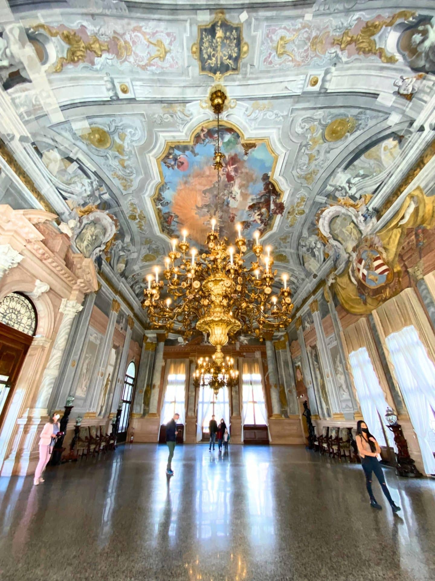 How to Spend One Day in Venice, Italy: A Simple Budget-Wise Itinerary 10 Ornate ballroom inside Ca' Rezzonico palace in Venice, Italy, featuring a grand chandelier, frescoed ceiling, and classical furnishings. The elegant room reflects Venetian Baroque style and historic opulence.