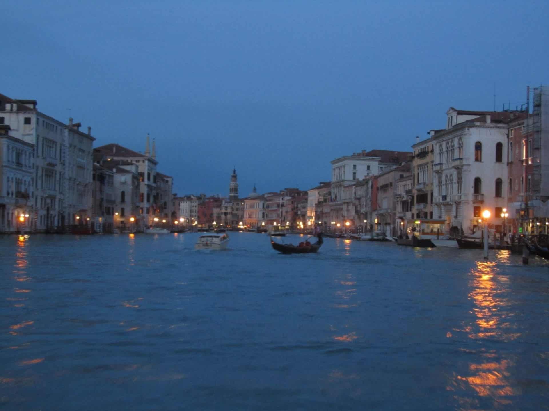 How to Spend One Day in Venice, Italy: A Simple Budget-Wise Itinerary 3 Twilight view of the Grand Canal in Venice, Italy, with historic buildings lining the water and lights reflecting off the canal as boats and gondolas cruise by.
