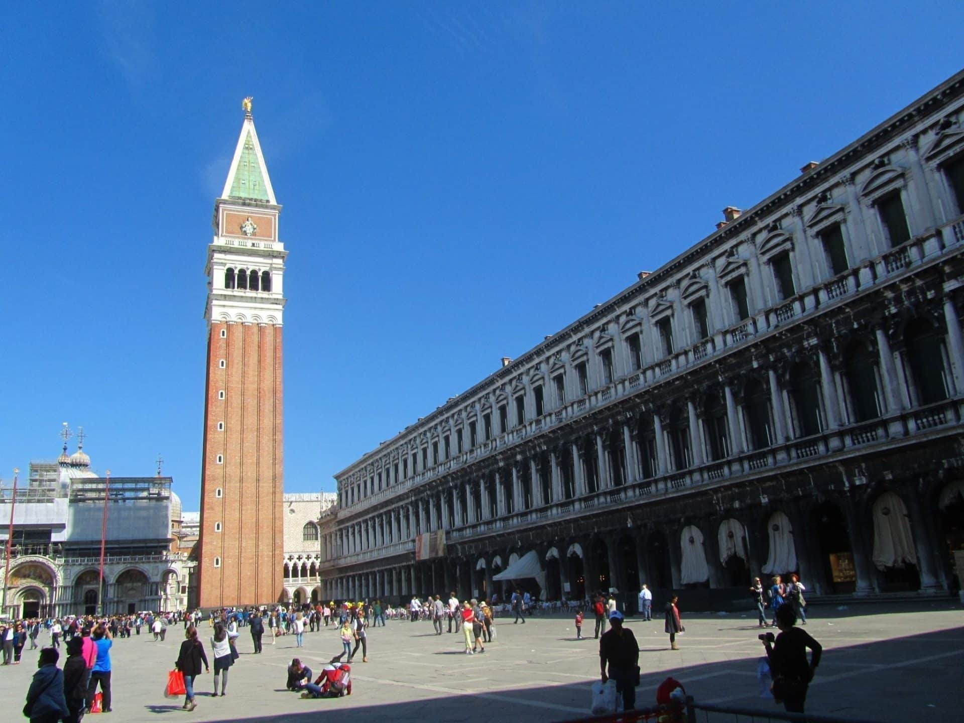 How to Spend One Day in Venice, Italy: A Simple Budget-Wise Itinerary 6 Piazza San Marco in Venice, Italy, with St. Mark's Campanile towering above the historic square. The open plaza is surrounded by elegant architecture, capturing the grandeur of one of Venice’s most iconic landmarks as tourists mill about.