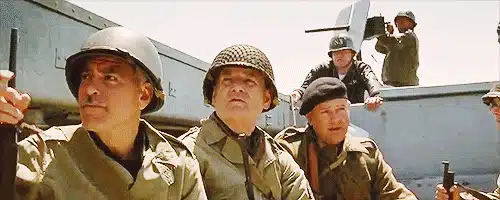 75 Movies Set in European Destinations to Inspire Your Next Trip 36 Animated Gif from The Monuments Men showing George Clooney and fellow cast members in World War II military uniforms in a vehicle while on a mission to save stolen art.