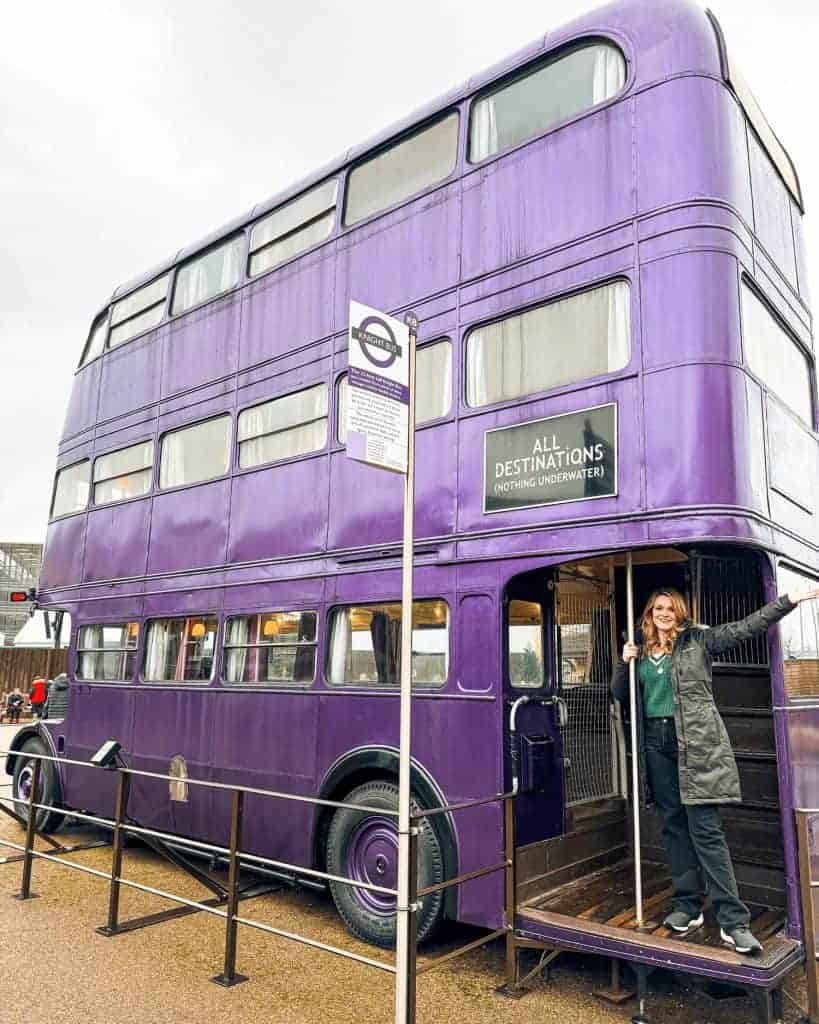 11 Amazing London Day Trips You Can Easily Take by Train in 2 Hours or Less 11 Woman in a winter coat poses in front of the iconic purple triple‑decker Knight Bus at Harry Potter Warner Bros. Studio Tour London.
