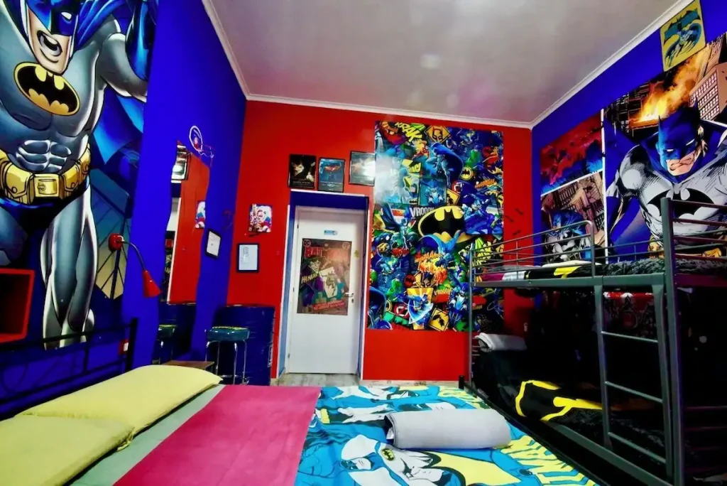 Reviewing Comics Guesthouse Roma as a Fan: Is It the Best Hostel in Rome, Italy? 4 Batman-themed room, decked out with vibrant murals, comic book posters, and matching bedding and decor at Comics Guesthouse hostel in Rome, Italy.