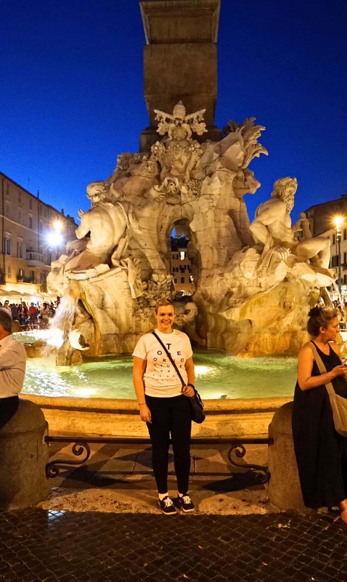 Home 37 Michelle L. Jensen (Travel HerStory) standing before the Fontana dei Quattro Fiumi (Fountain of the Four Rivers) in Piazza Navona, Rome, Italy. Designed by Gian Lorenzo Bernini in 1651, the fountain features personifications of four major rivers representing four continents: the Nile (Africa), the Ganges (Asia), the Danube (Europe), and the Río de la Plata (Americas).