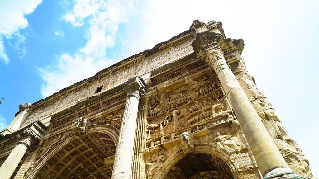 What It's Like to Visit the Roman Forum: A Visual Guide to Rome's Epic Ruins 29 Arch of Septimius Severus at the Roman Forum near Palatine Hill in Rome, Italy, a triumphal marble structure adorned with intricate carvings and flanked by weathered columns.