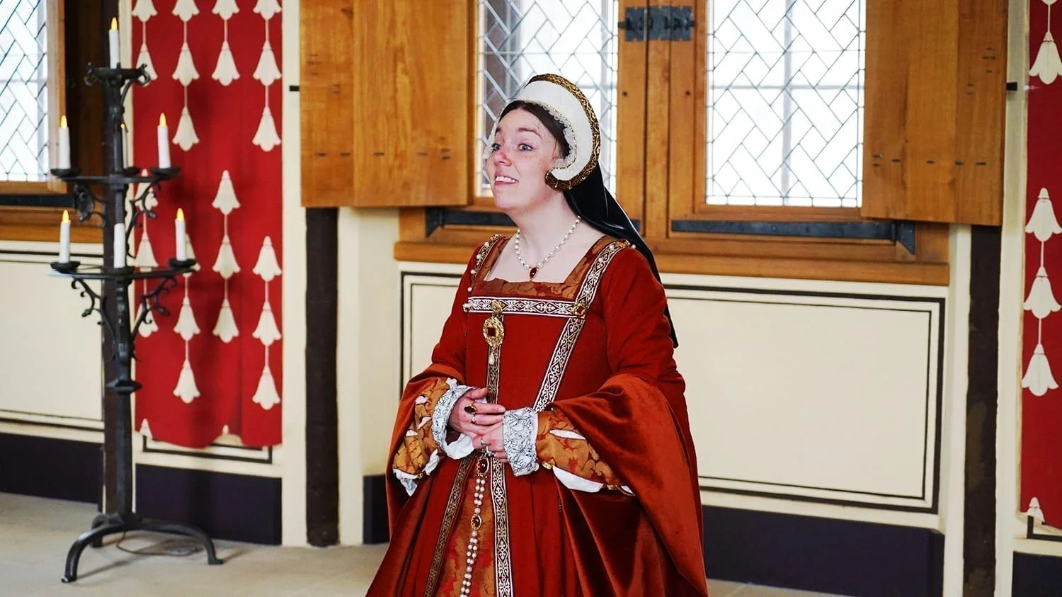 How to Visit Stirling Castle, Scotland: An Easy Day Trip by Train 16 Woman in historical costume at Stirling Castle wearing a red and white Renaissance-style gown, standing in a period-decorated room with ornate furnishings.