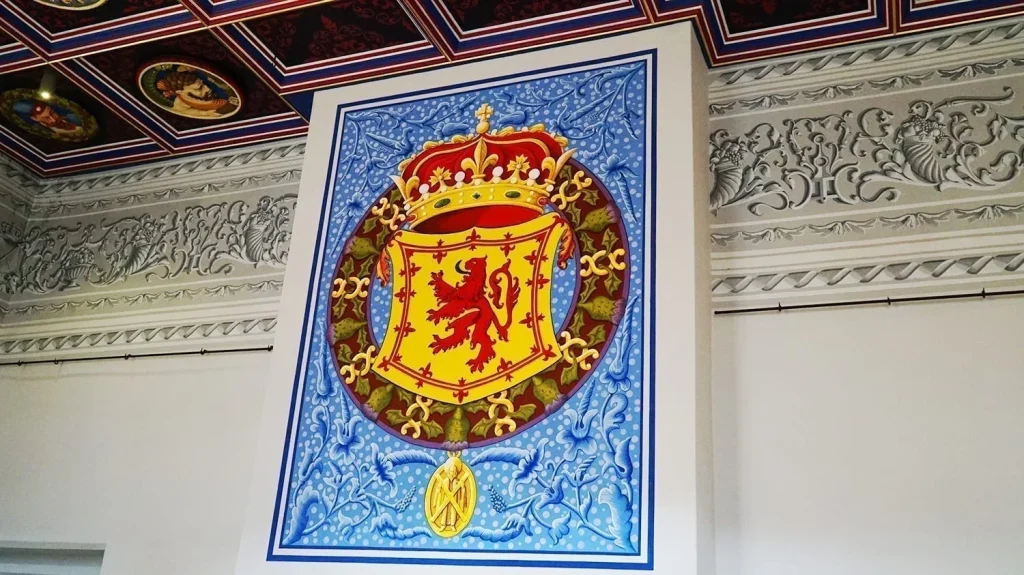 How to Visit Stirling Castle, Scotland: An Easy Day Trip by Train 9 Crowned shield in front of a blue painted background over a fireplace in the King’s Old Building, in Stirling Castle, Scotland.