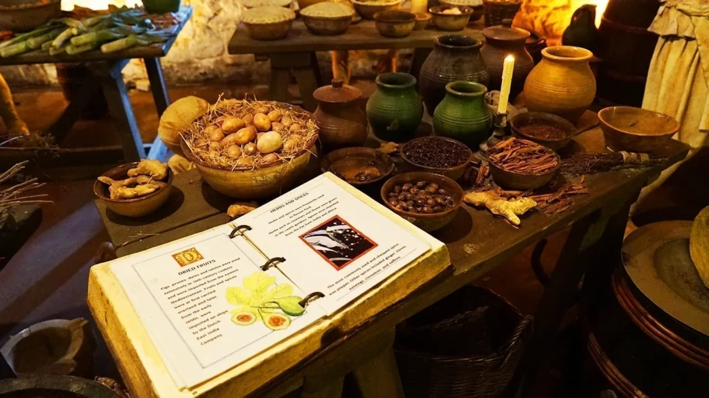 How to Visit Stirling Castle, Scotland: An Easy Day Trip by Train 24 Medieval meal display at Stirling Castle, showing a recipe book, bowls filled with grains, vegetables, and cooked dishes on a rustic wooden table in a period kitchen.