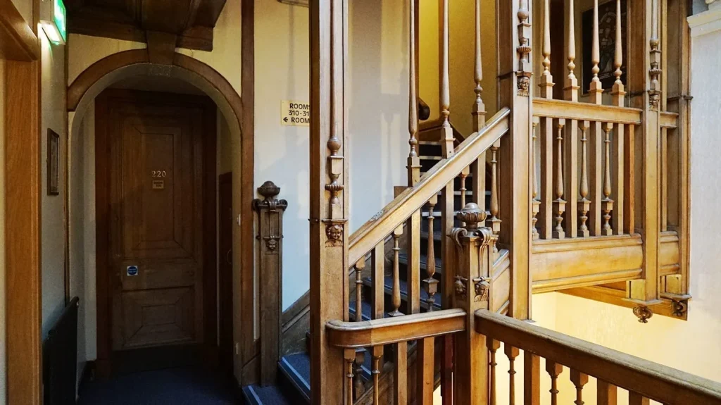 Glasgow Youth Hostel Review: Is it the Best Place to Stay? 3 Interior staircase of the SYHA Glasgow hostel, featuring a wooden banister along the cream-colored walls.