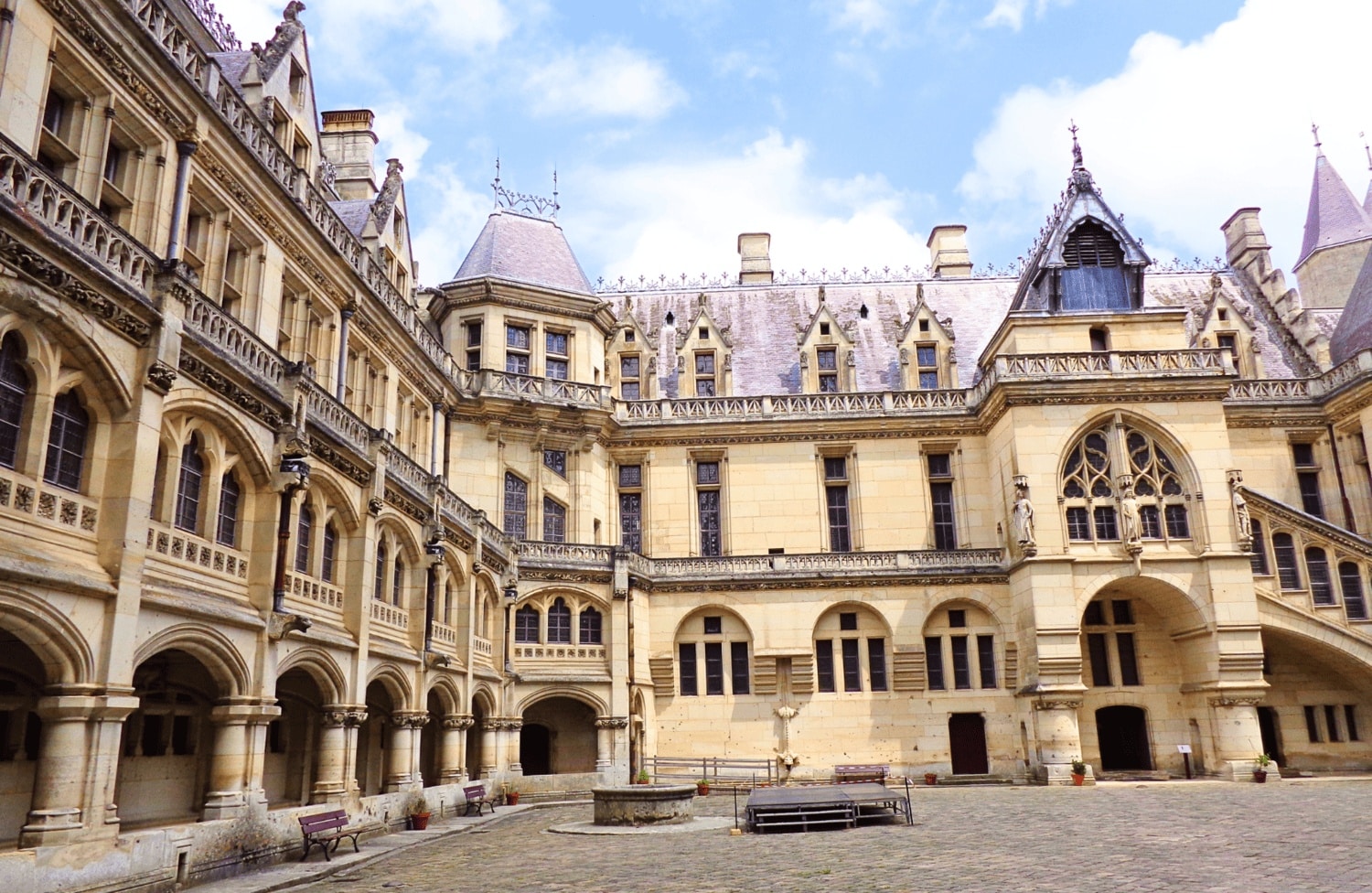 Exterior view of the fairytale-like Château de Pierrefonds, France, courtyard with its towers and stone walls under a clear sky, which is included with the Paris Museum Pass.