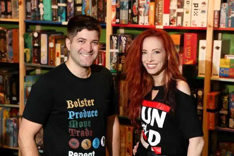 21 Cool, Nerdy Things to Do in LA—Activities for Kids to Adults 17 Donna Ricci, owner of Geeky Teas & Games in Burbank, CA, standing inside the store with another person. Surrounded by shelves of board games, fandom merchandise, and tabletop gaming supplies, the cozy space reflects the shop’s role as a local community hub for geeks and gamers.
