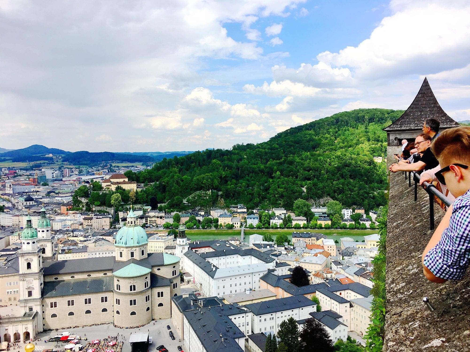 Visitors looking out from the top of Hohensalzburg Fortress, enjoying panoramic views of Salzburg, Austria, and the surrounding landscape.
