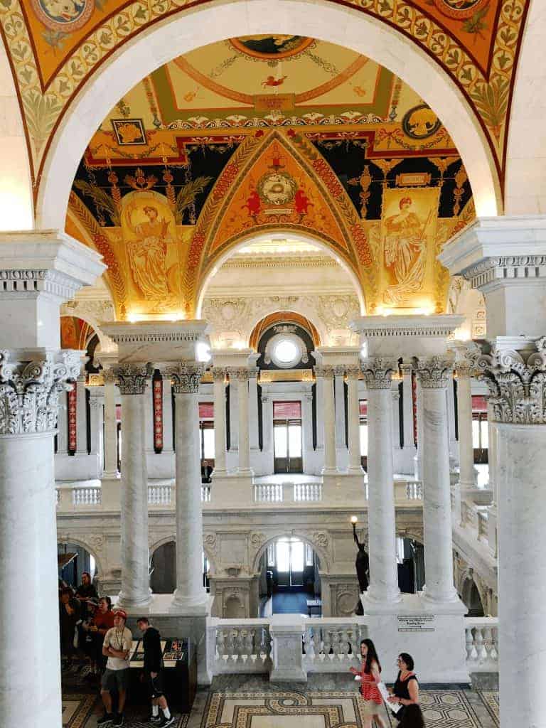Literary Travel 17 Ornate interior of the Library of Congress in Washington DC, USA, with grand arches, marble columns, intricate ceiling murals, and decorative carvings in the richly detailed entrance.