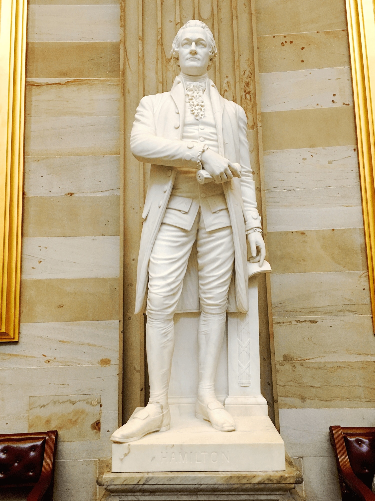 USA 18 Statue of Alexander Hamilton in the U.S. Capitol, depicting him in 18th-century attire standing atop a stone pedestal, surrounded by the historic government building in Washington DC.