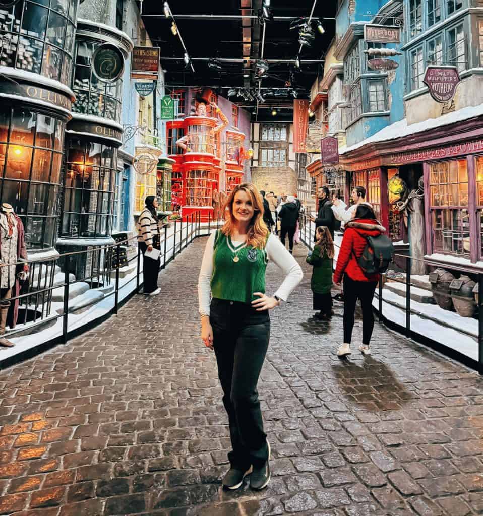 11 Amazing London Day Trips You Can Easily Take by Train in 2 Hours or Less 10 Woman dressed in Harry Potter-themed Slytherin attire on the snowy Diagon Alley street during a tour in London of the Harry Potter Studios.