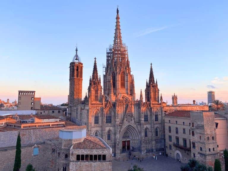 Barcelona Cathedral at sunset in Spain, with its Gothic spires glowing in warm light, set against a vibrant sky in the historic Gothic Quarter.