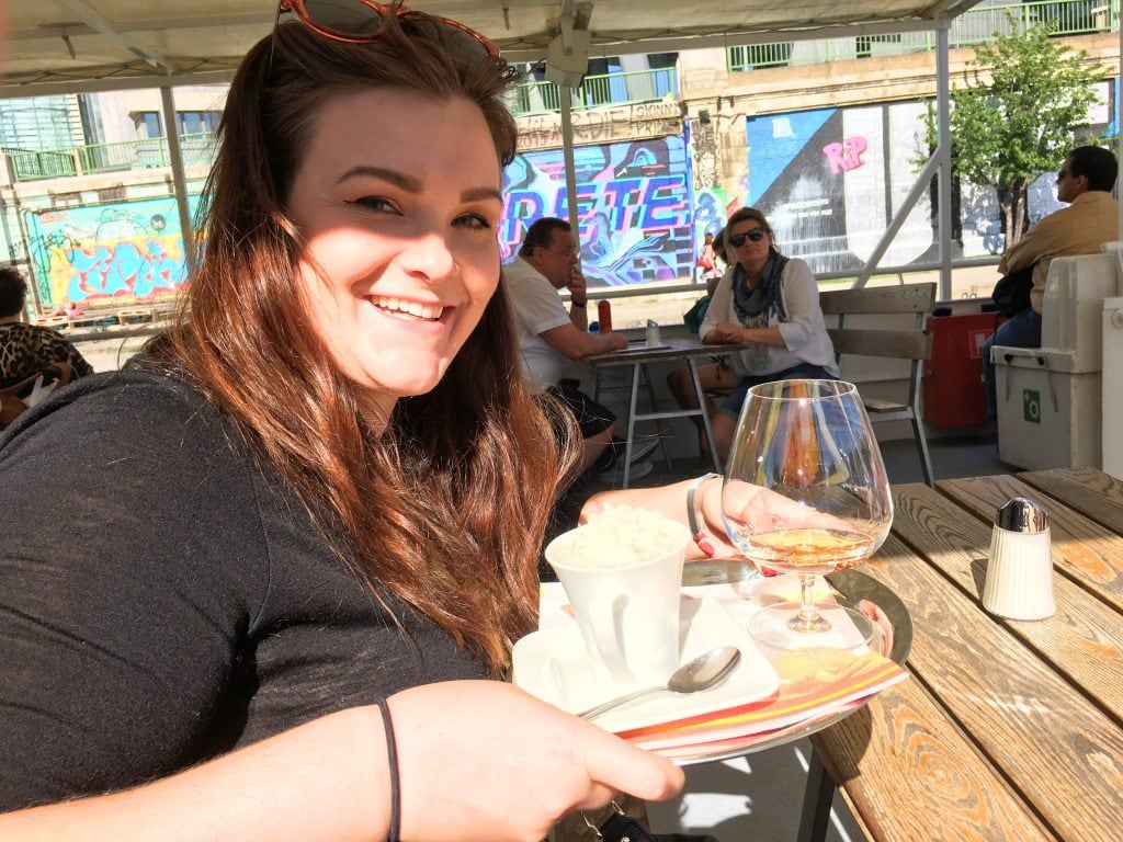 Where to Stay in Vienna, Austria: My Favorite Areas + Best Budget Hotels 2 Woman holding plate with mug and glass on it on a City Cruise in Vienna Austria