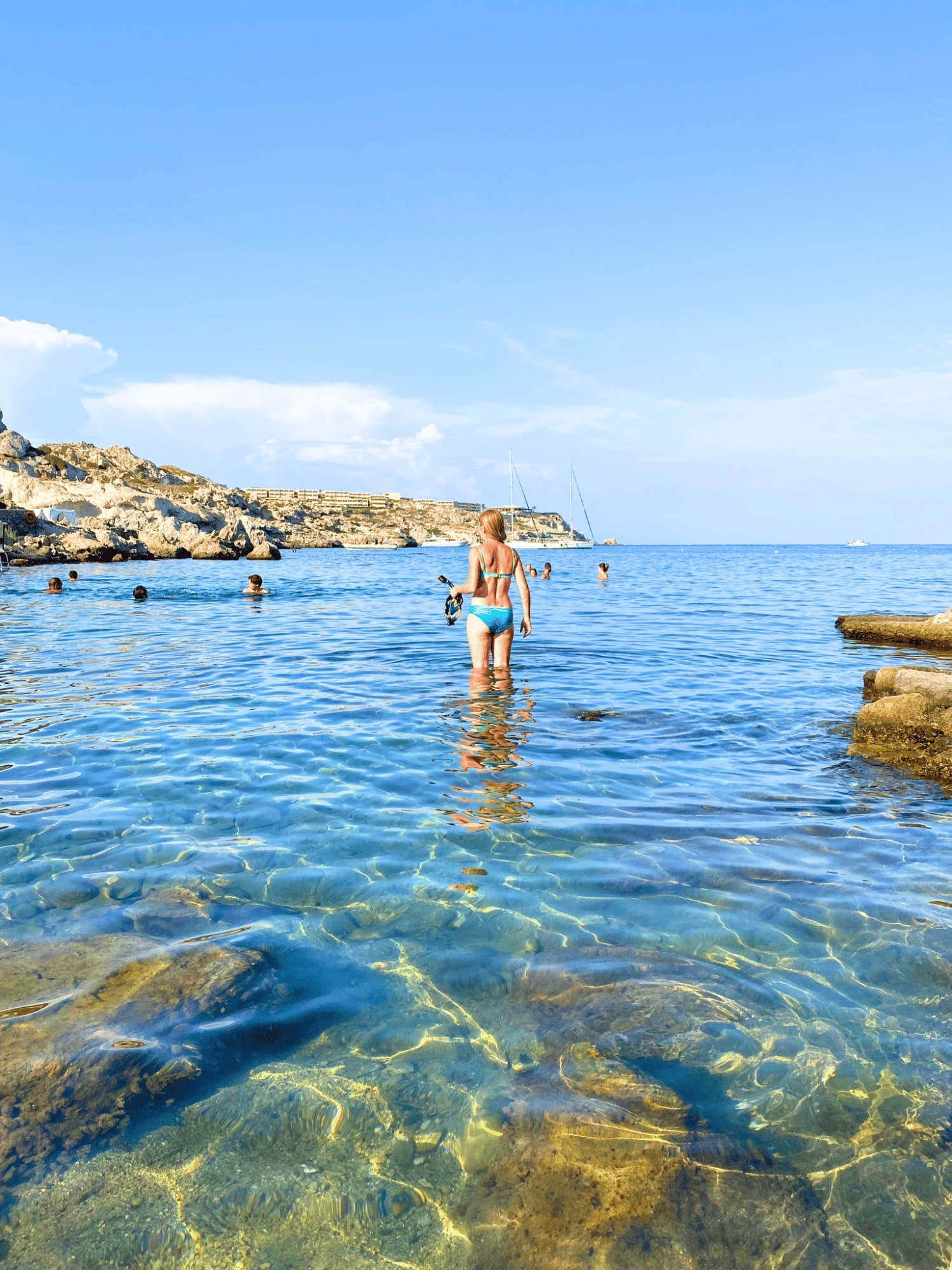 Travel Guide for Rhodes, Greece: Everything First-Time Visitors Need to Know 11 Woman swimming in crystal clear waters at Ladiko Beach, Rhodes, Greece.