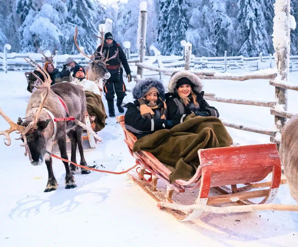 Two women taking part in an enchanting Reindeer Sleigh Ride in Finland.