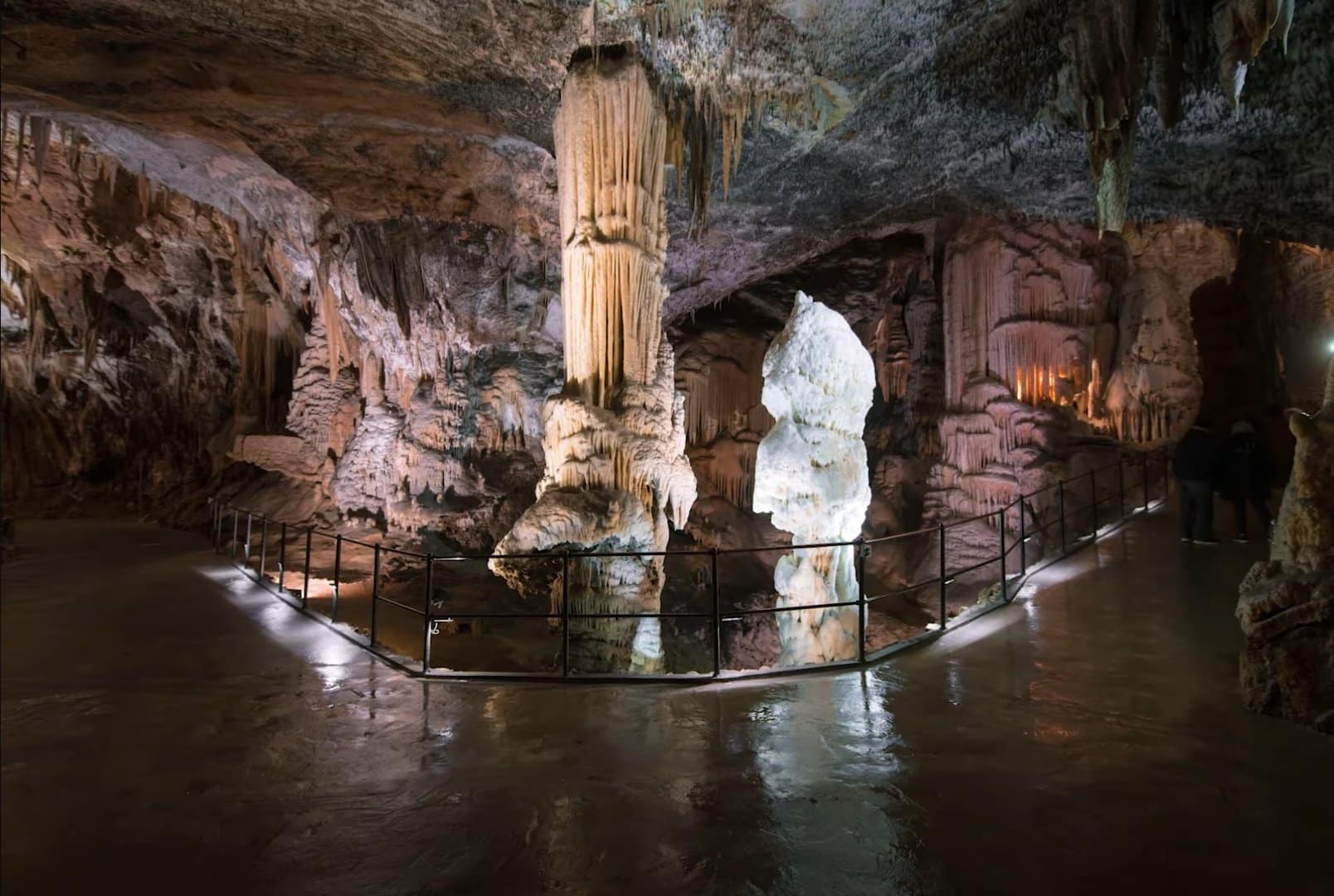 Slovenia 9 Pathway through the Postojna Cave in Slovenia, featuring illuminated limestone formations including large stalactites and stalagmites inside a vast underground chamber.