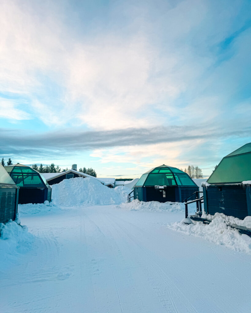 The Best Hotels in Rovaniemi, Finland: Comparing My Glass Igloo Stay with the City Center 16 Arctic SnowHotel glass igloos in daytime for a snowy landscape vacation retreat.