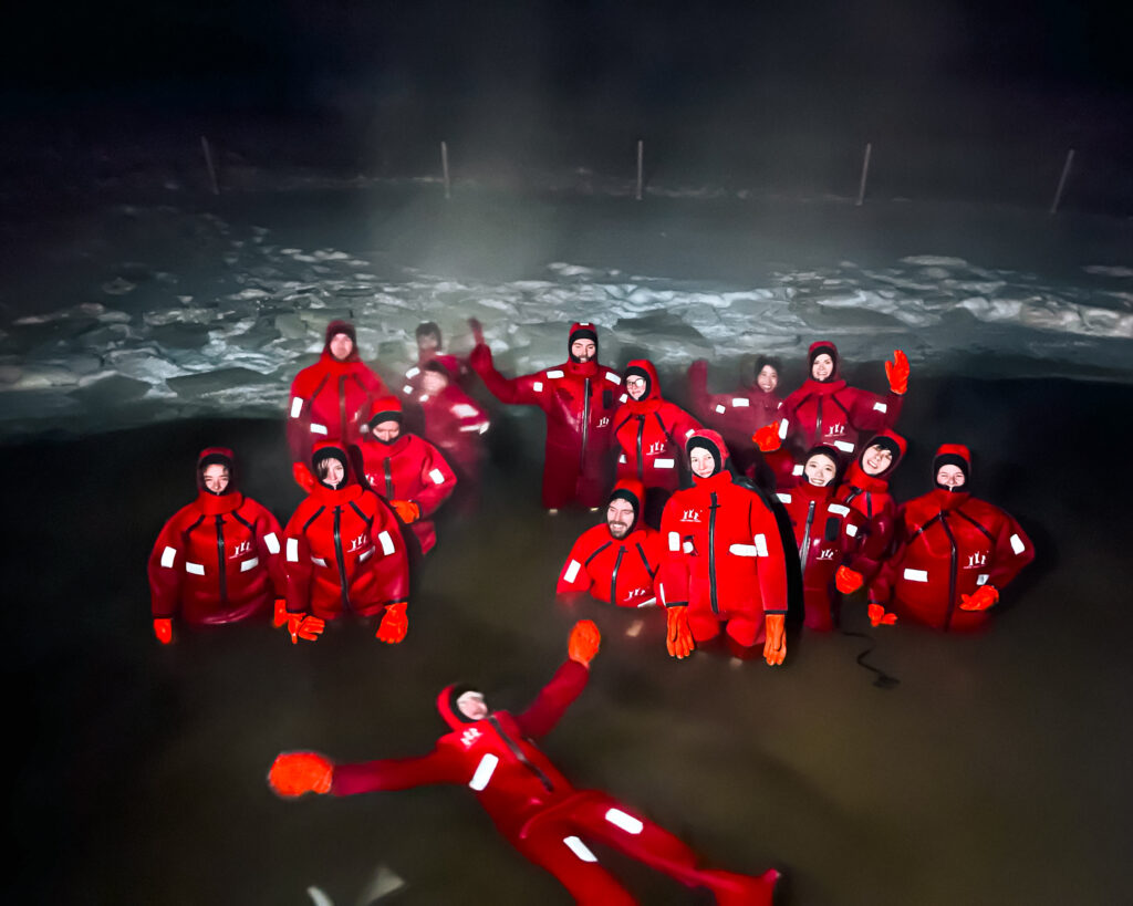 My Epic Experience Ice Floating in Rovaniemi, Finland: Honest Tour Review 6 Group of people enjoying winter activities in red Ice Floating suits in Lapland.