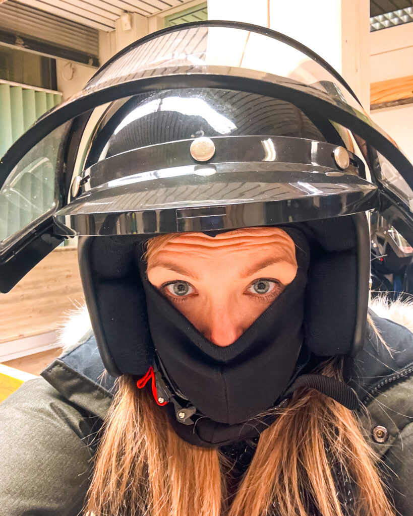 30 of the Best Things to Do in Rovaniemi, Finland, This Winter 30 Woman enjoying snowmobiling safari in Rovaniemi, wearing a helmet.