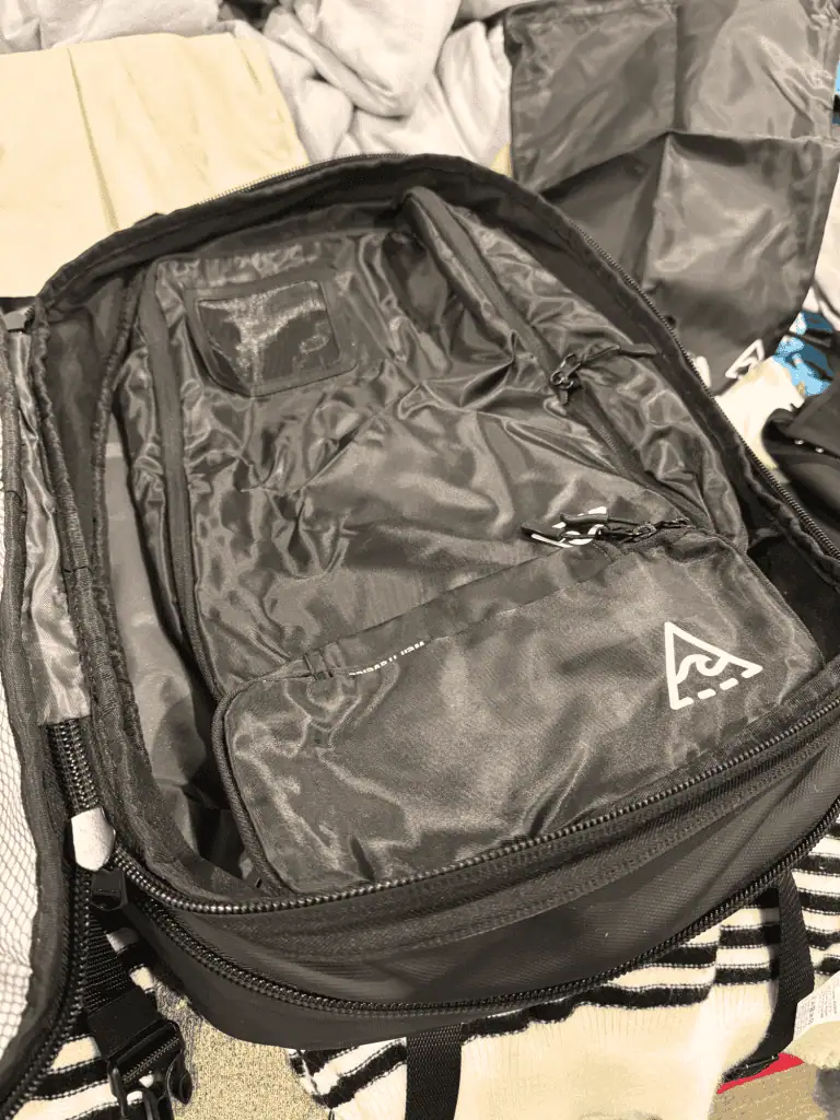 Hostel Packing List for Females: My 38 Essentials + 4 Items I Skip Entirely 5 Black voyage travel backpack with Well Traveled compression packing cubes laid on top for organization.