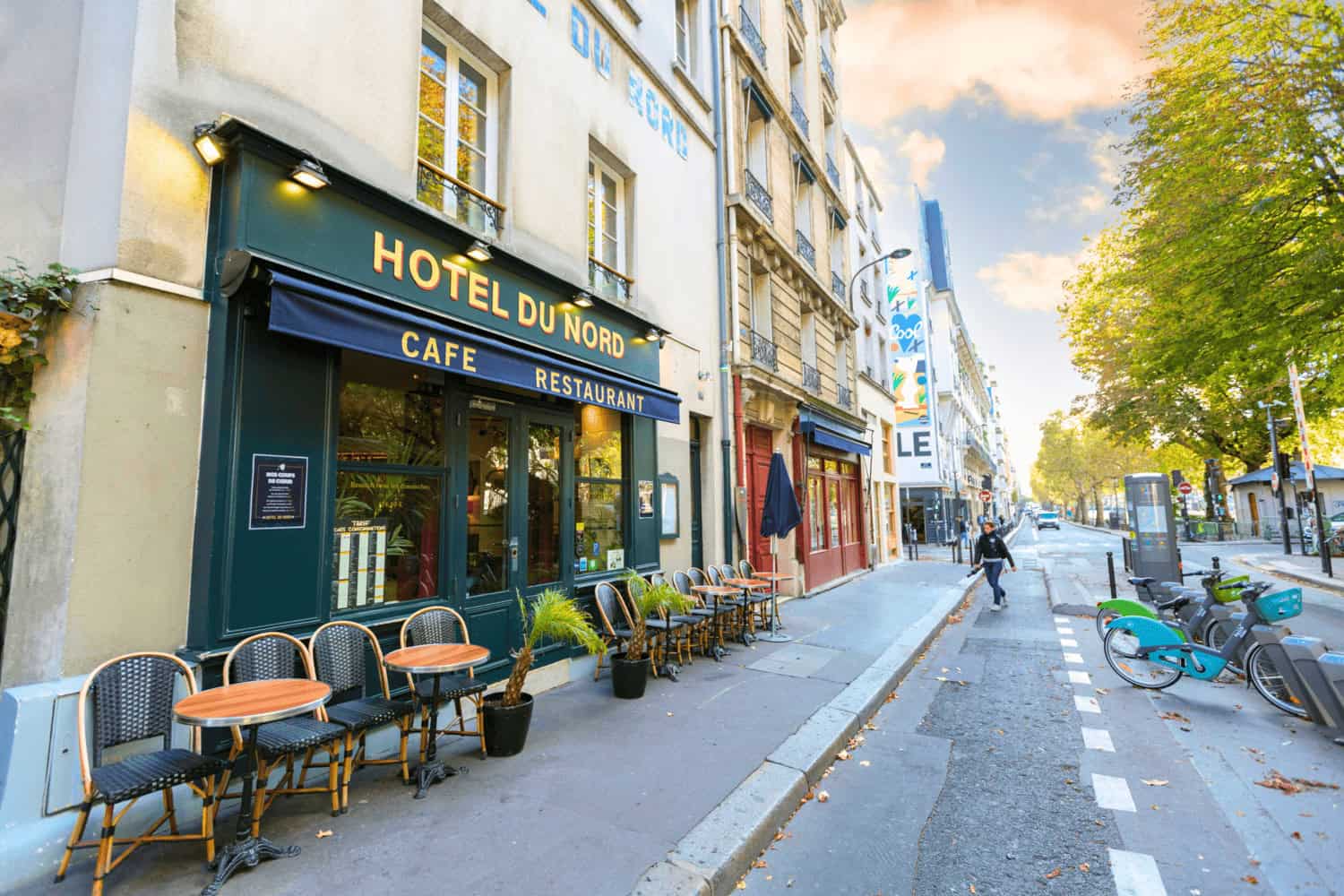 Brasserie de l'Hôtel du Nord with outdoor seating under a blue awning, warm lights, and vintage signage in Paris, France.