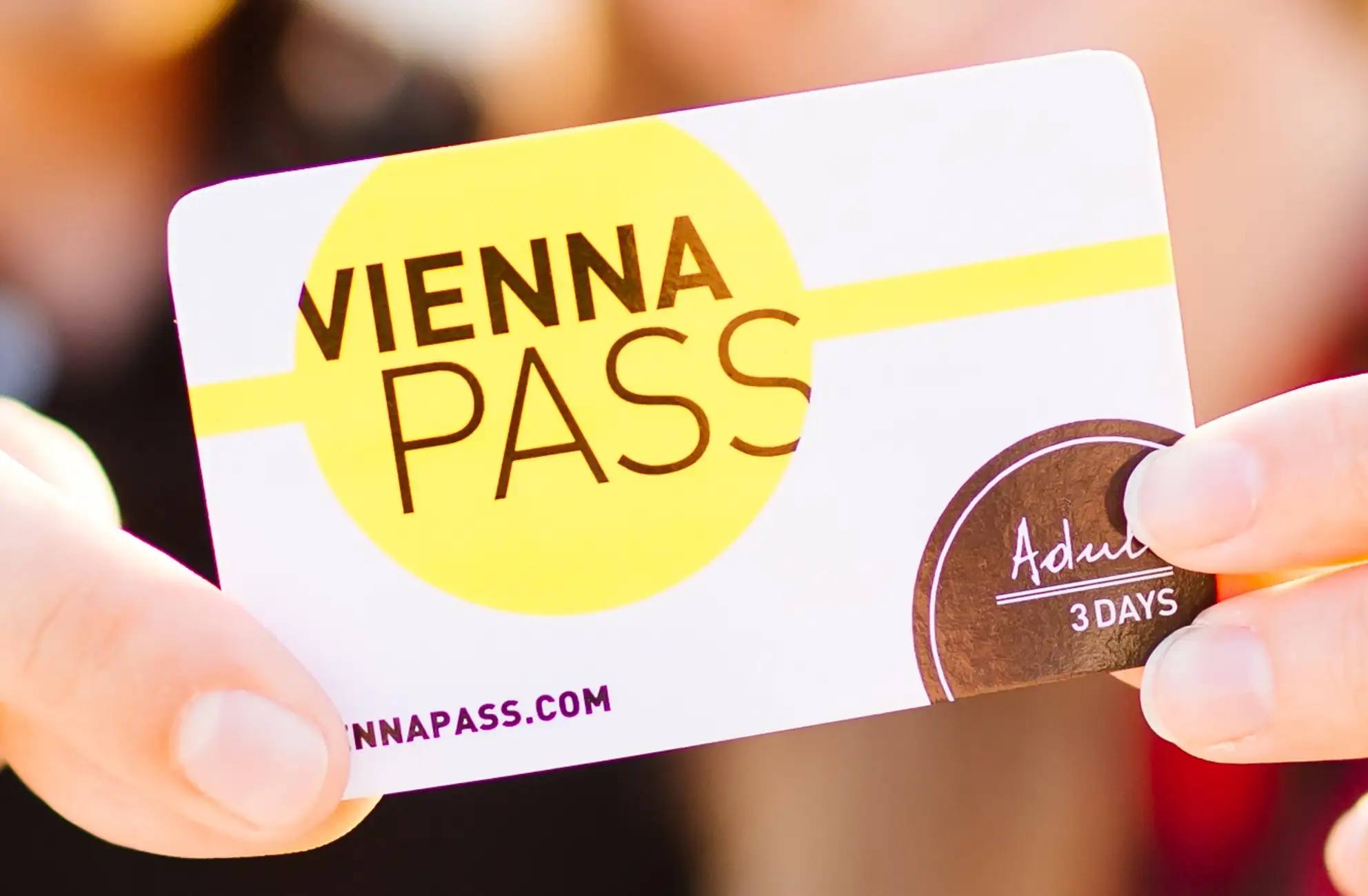 Austria 31 Fingers holding the Vienna Pass, their 3-day card for adults, featuring a yellow, white, and black design with their website and logo.