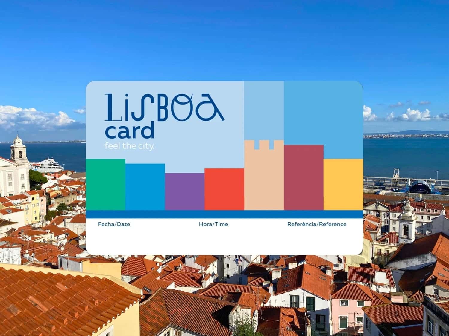 Lisboa Card tourist pass displayed over a sweeping viewpoint of Lisbon, Portugal's Alfama district, showing terracotta rooftops, a white church bell tower, and the wide blue Tagus River estuary stretching to the horizon under a partly cloudy sky.